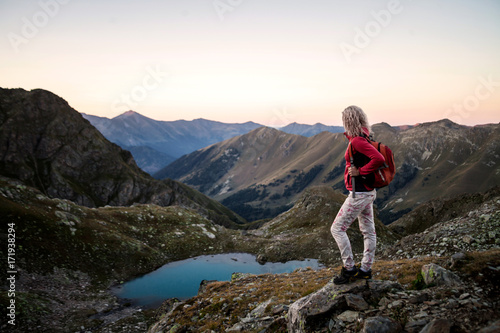 Girl hiker standing on a brink rock and looking at the mountains