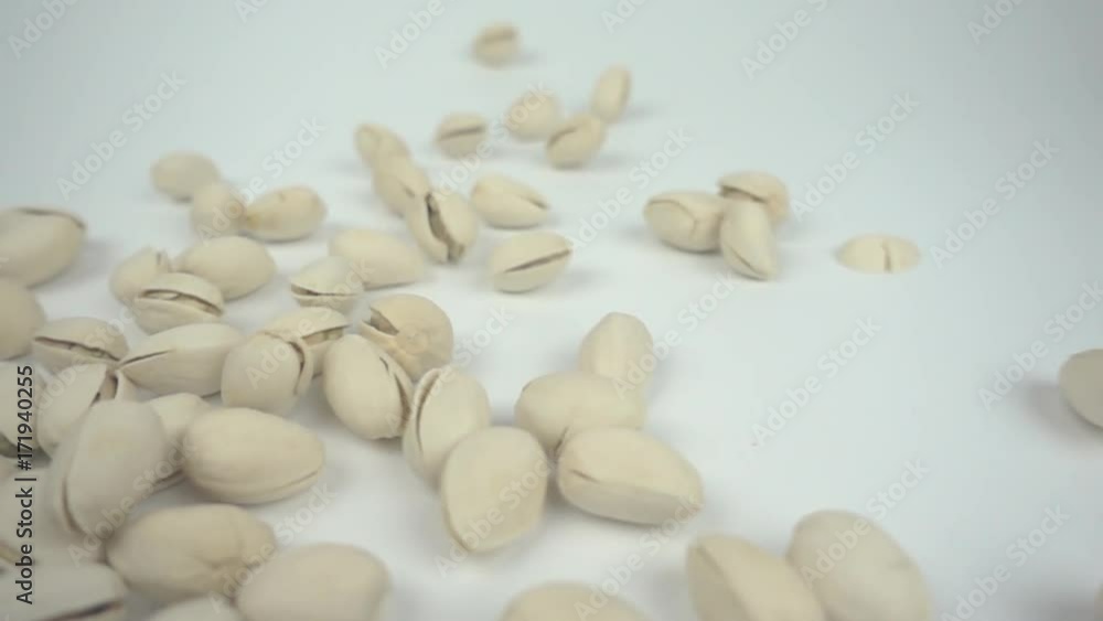 Pistachio nuts falling in slow motion from left to a white background Pistachio nuts falling in slow motion from left to a white background