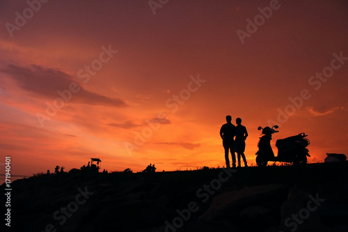 couples having sunset at beachside a scooter near to them