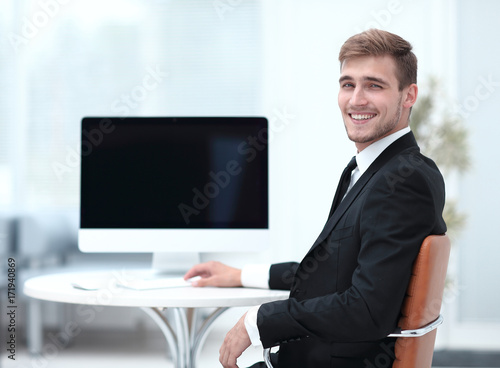 successful businessman sitting at Desk and looking at camera.