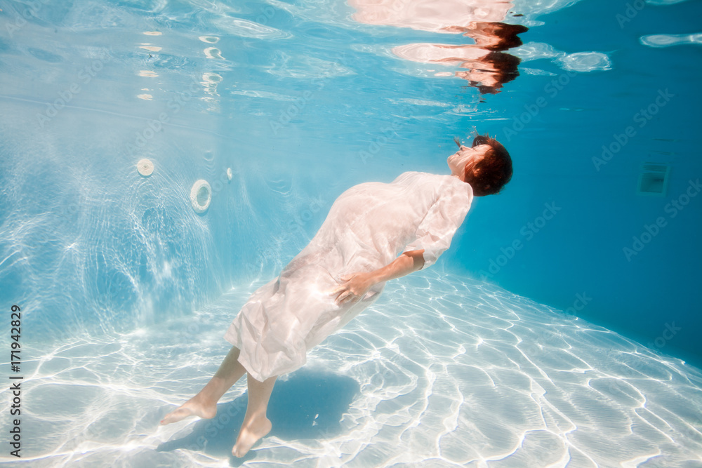 Pregnant woman swim, dive, pose underwater in swimming pool with red fabric. Aqua fitness