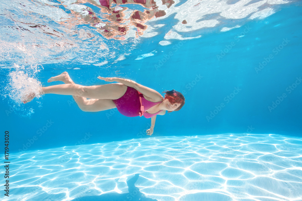 Pregnant woman swim, dive, pose underwater in swimming pool with red