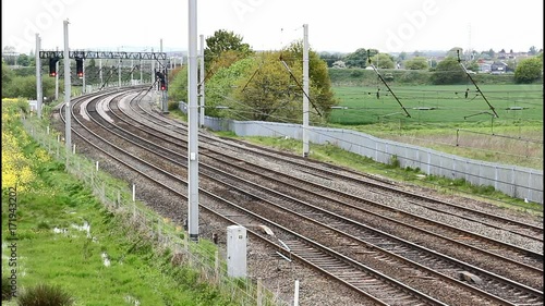 Section of electrified four track mainline railway on the west coast main line of England. There are no trains in this clip but light car traffic is passing in the background. Signals are red. photo