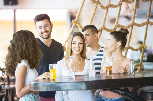 Group of friends talking and drinking at bar photo