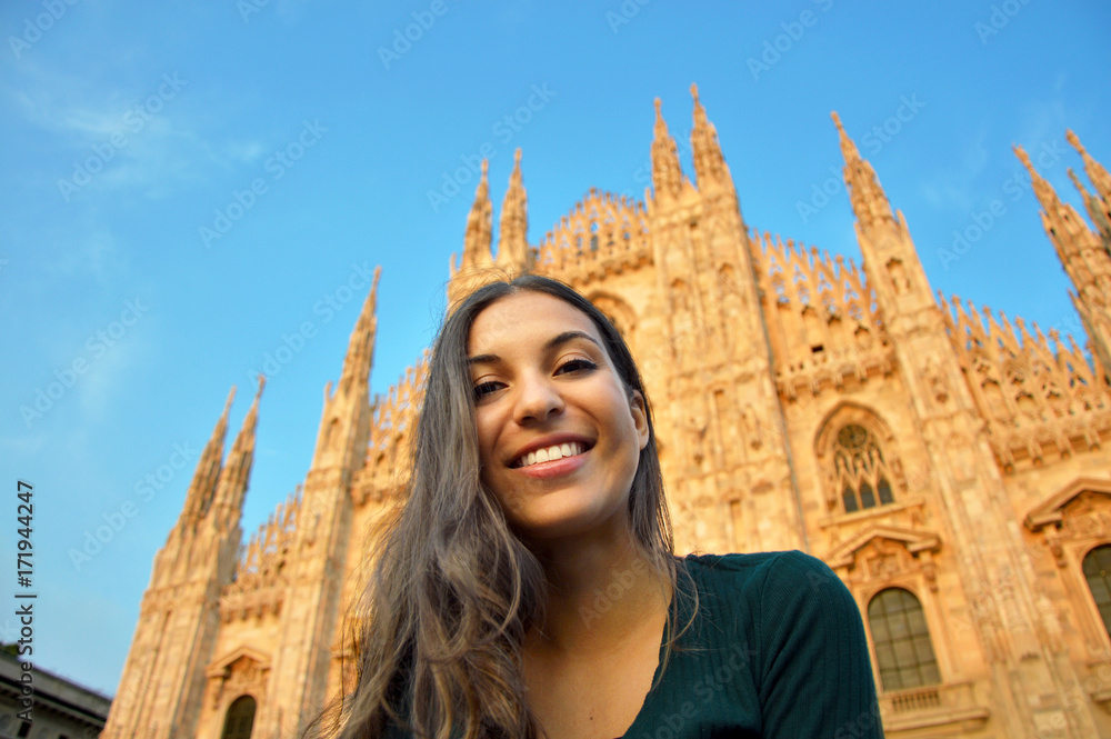 Beautiful happy young woman smiling in front of the famous Duomo Cathedral in Milan at sunset. Europe travel, Italy 