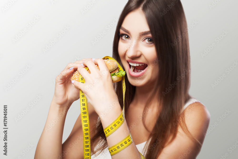 Diet. Harmful and useful food. A young girl makes a choice either for a diet or for a meal. Sport. The concept of health and beauty. On a gray background. Diet. Harmful and useful food. A young girl makes a choice either for a diet or for a meal. Sport. The concept of health and beauty. On a gray background.