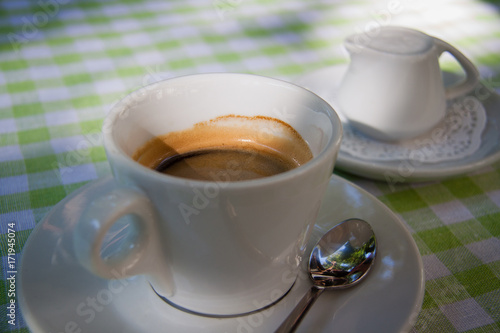 White cup of coffee with milk in the country garden