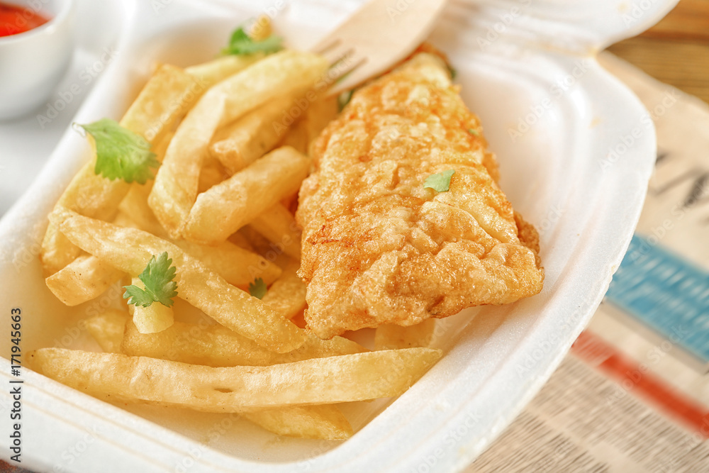 Tasty fried fish and potato chips in lunchbox on table, closeup Tasty fried fish and potato chips in lunchbox on table, closeup