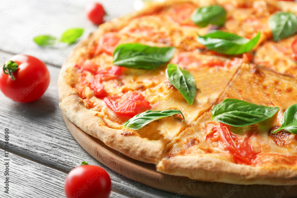Delicious pizza with tomatoes and fresh basil on kitchen table Delicious pizza with tomatoes and fresh basil on kitchen table