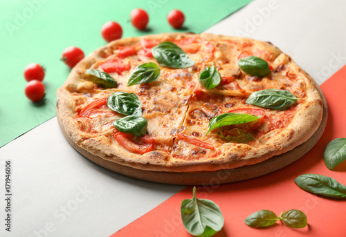 Composition with pizza, cherry tomatoes and fresh basil on Italian flag on background