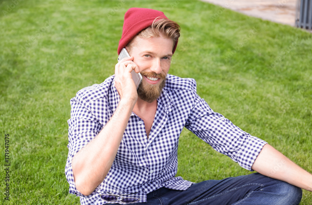 Young hipster man talking on phone in park Young hipster man talking on phone in park