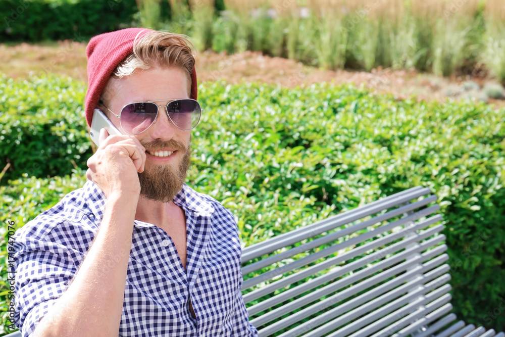 Fototapeta premium Young hipster man talking on phone in park