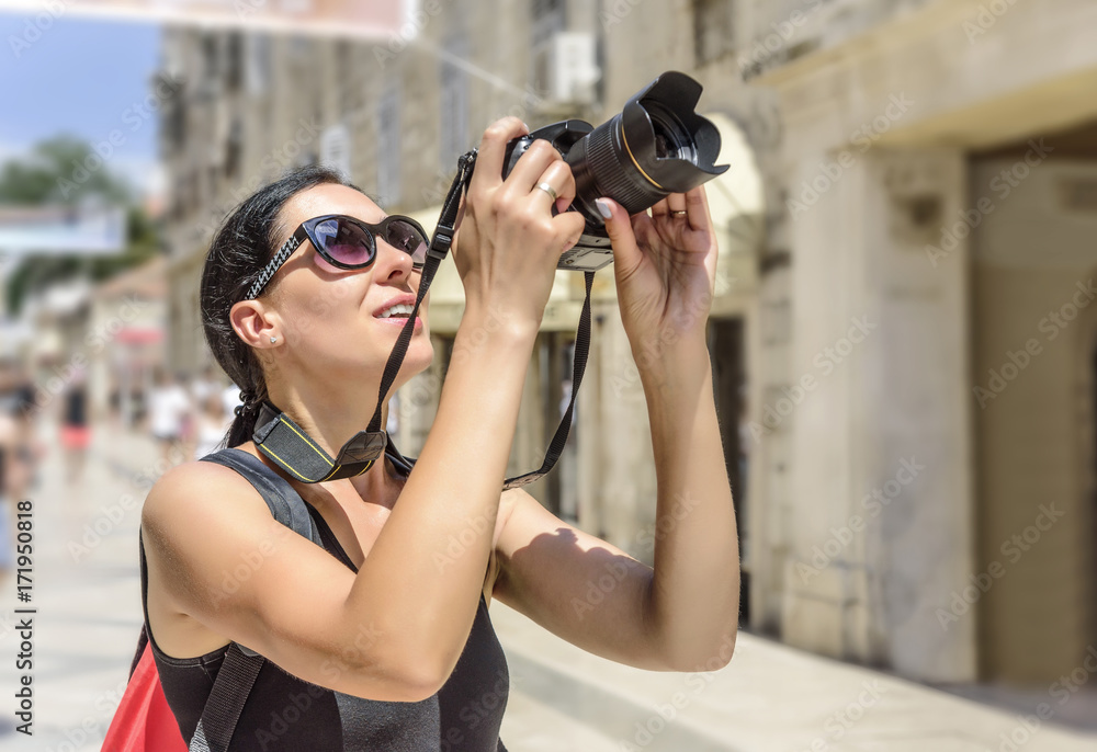 Tourist with a camera photographing the streets on a sunny day.