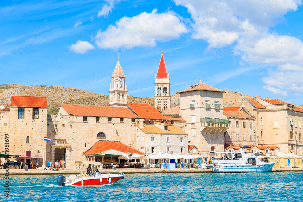 Motorboat sailing on sea along Trogir old town with historic buildings, Dalmatia, Croatia