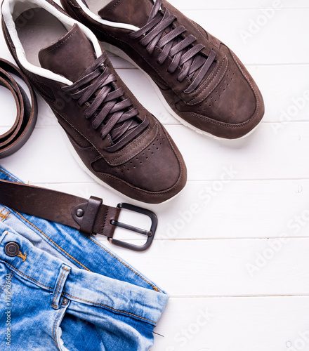 male jeans, belt and shoes on wooden background, top view