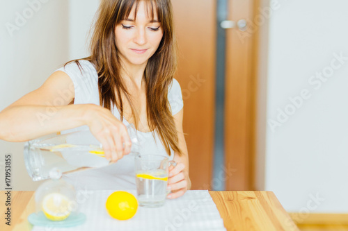 Drink water. Woman's hand pouring fresh pure water with pieces of lemon from pitcher into glass in the morning Health and diet concept. Healthy lifestyle. Healthcare and beauty. Hydratation.