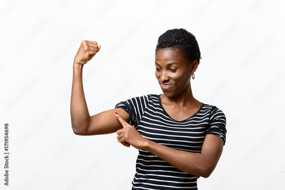Young African woman pointing to her arm muscles Young African woman pointing to her arm muscles