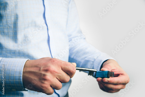 Man holds a key in his hand and tries to open USB memory. Cyber security and data security on the memory card against hacking. Isolated  white background.