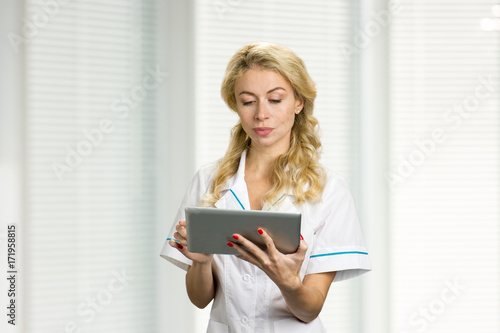 Young nurse working on computer tablet. Confident young female medical doctor using digital tblet.