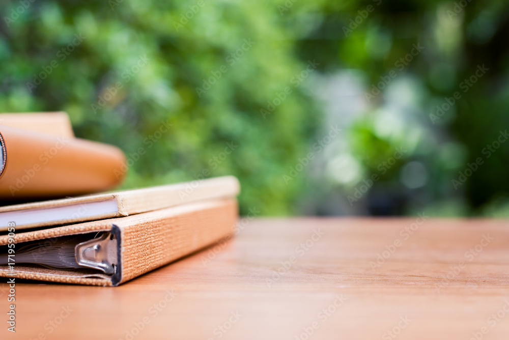 Books on a wooden desk at the in front of house with blurred garden view textured background. Books on a wooden desk at the in front of house with blurred garden view textured background.