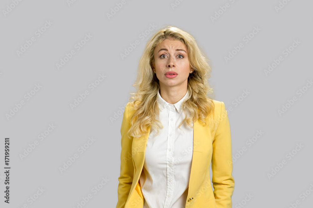 Confused young woman, grey background. Portrait of amusing confused young woman with long blond hair over grey background. Confused young woman, grey background. Portrait of amusing confused young woman with long blond hair over grey background.
