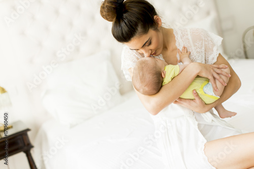 Young mother and cute baby girl on the bed