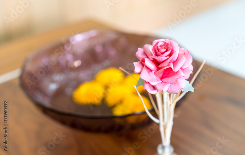 Artificial pink rose on wooden table