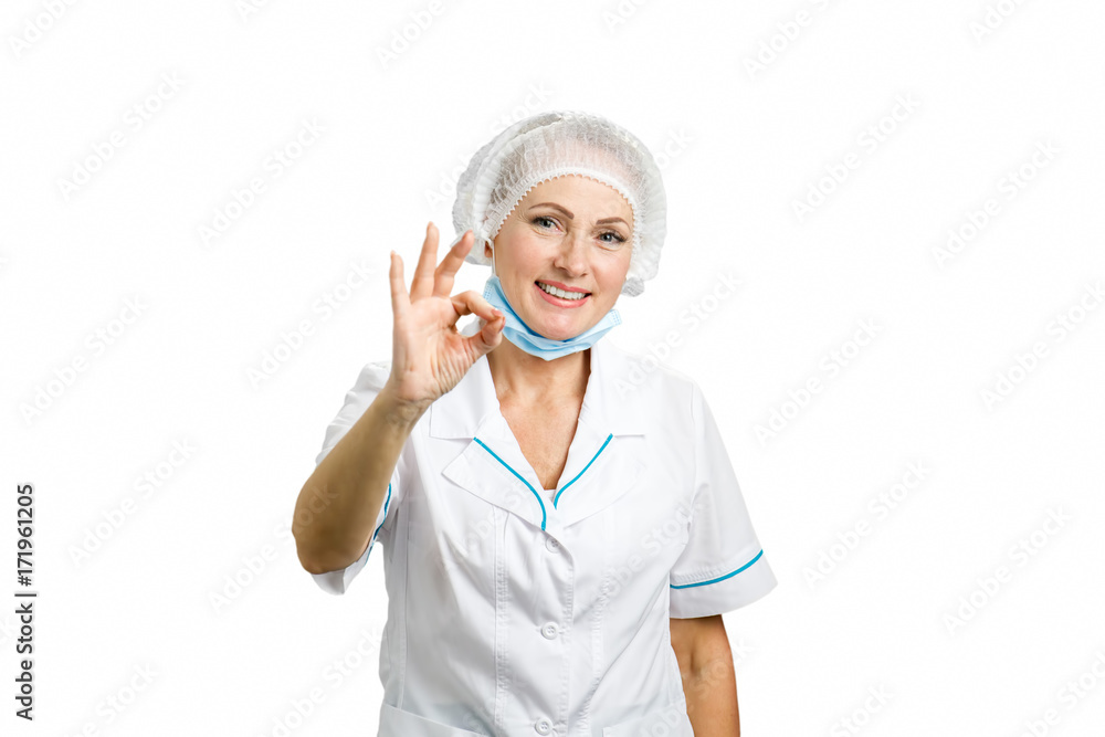 Smiling female surgeon gesturing ok. Cheerful beautiful mature woman doctor showing ok gesture over white background. Smiling female surgeon gesturing ok. Cheerful beautiful mature woman doctor showing ok gesture over white background.