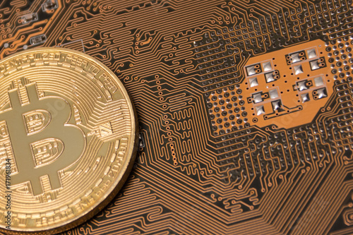 Close-up of a gold bitcoin on a computer motherboard. photo