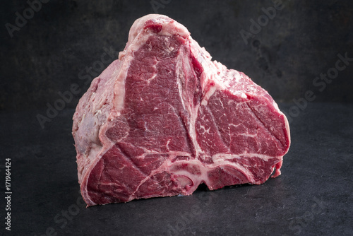 Raw dry aged wagyu porterhouse steak as close-up on a black slate