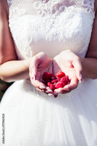 Girl bride holding raspberries in hands summer time joy vertical