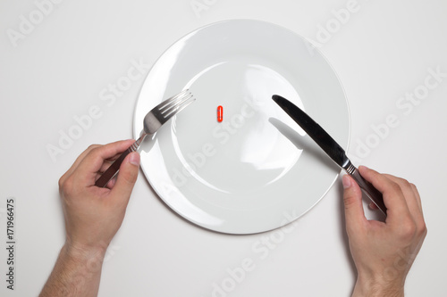 Pearson eating a red pill from a white plate with knife and fork, isolated on white background photo