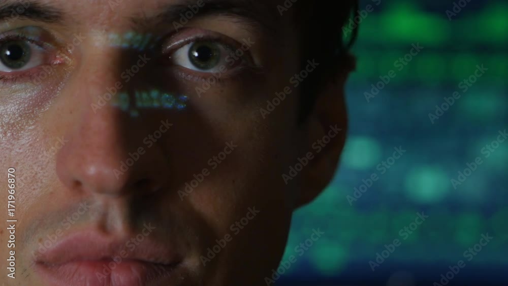Portrait of Man programmer hacker with green code characters reflect on his face with a computer screen on the background Portrait of Man programmer hacker with green code characters reflect on his face with a computer screen on the background