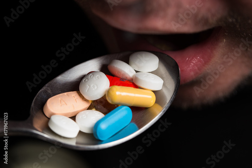Man eating pills with a spoon