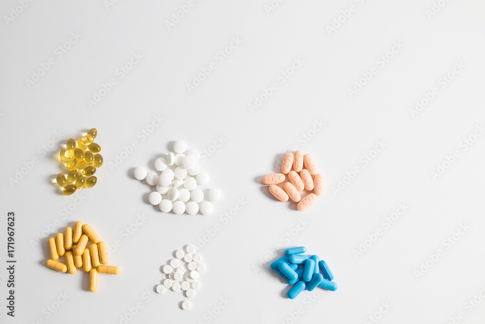 Groups of different colors pills on a white background