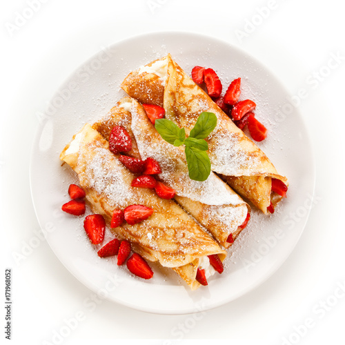 Crepes with strawberries and cream on white background 
