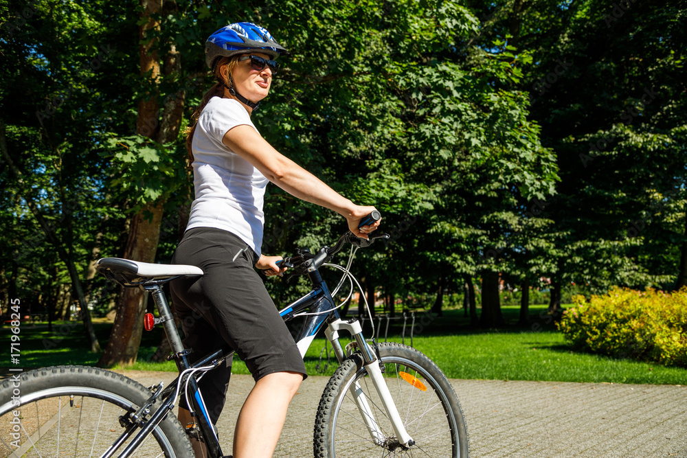 Healthy lifestyle - woman riding bicycle in city park 