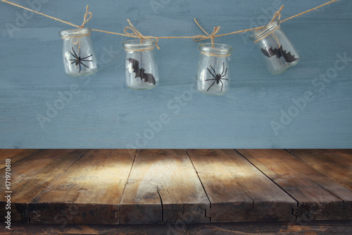 Halloween holiday concept. Empty old wooden table in front of masson jars with spiders and baths decorations