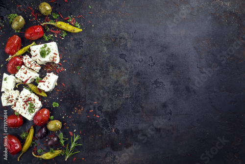 Traditional Greek feta with vegetable and peperoni as top view with copy space right on an old rustic board photo