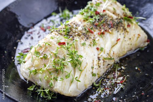 Fotomural Fried cod fish fillet with spice and cress as close-up in a cast iron pan
