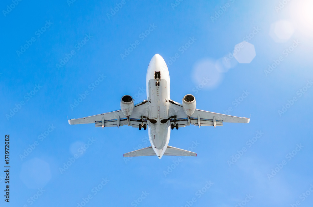 Fototapeta premium White passenger airplane landing at airport in the blue sky