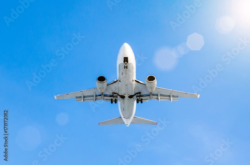 White passenger airplane landing at airport in the blue sky
