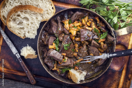 Fresh fried veal liver with chanterelle and baguette in sauce as top view in a casserole photo