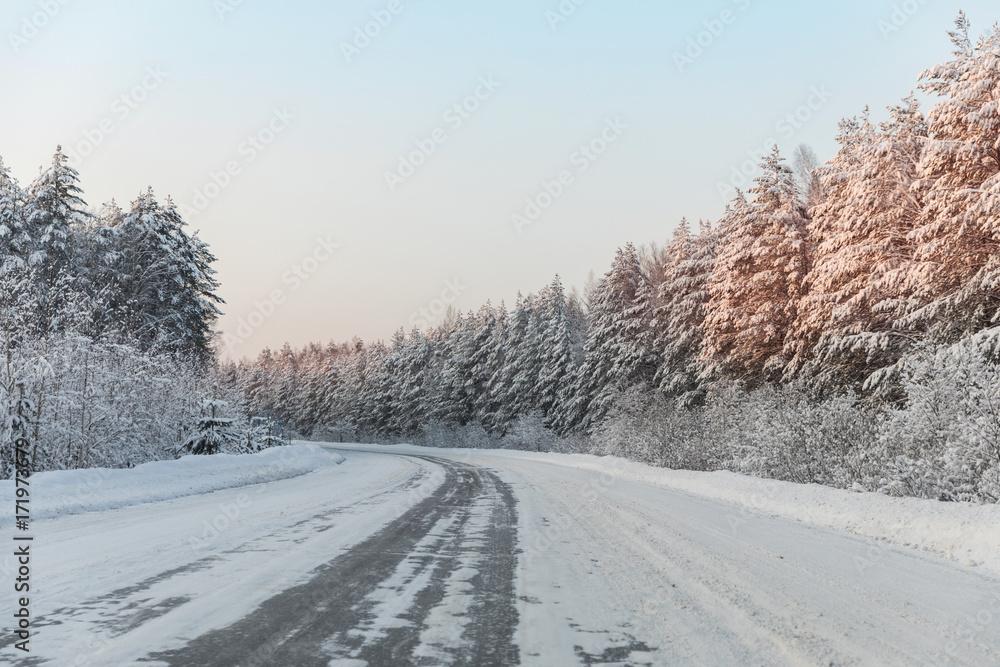winter road with ice on the asphalt, trees under snow during the winter frost winter road with ice on the asphalt, trees under snow during the winter frost