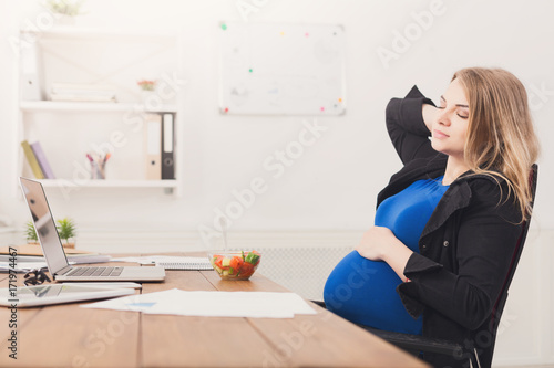 Pregnant businesswoman eating salad at office