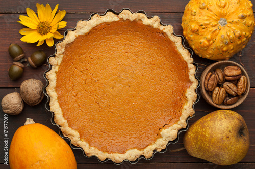 pumpkin homemade pie at wooden background arranged with food ingredients top view