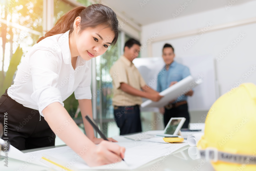 Asian woman engineer working with the tool on project drawings and brainstrom with engineering team in meeting room at infrastructure site. Asian woman engineer working with the tool on project drawings and brainstrom with engineering team in meeting room at infrastructure site.