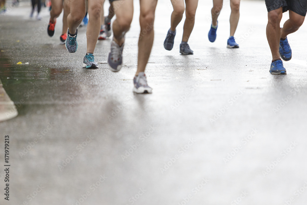 Marathon runners focus clear running shoes on the street with rain.