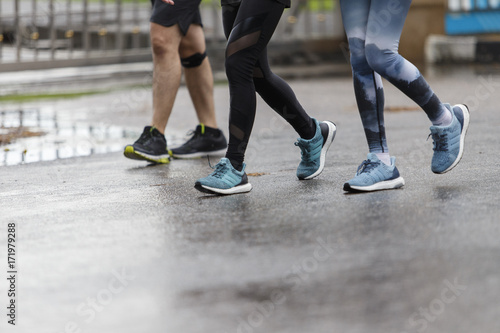Marathon runners focus clear running shoes on the street with rain.