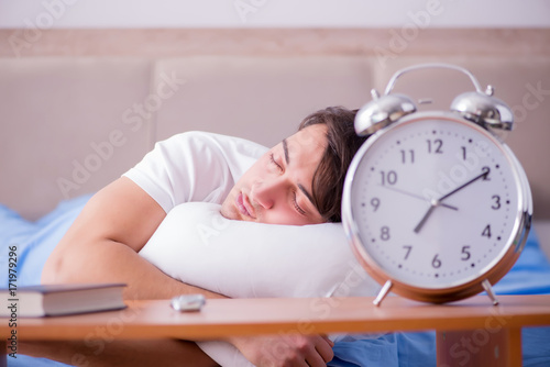 Man in bed frustrated suffering from insomnia with an alarm cloc photo